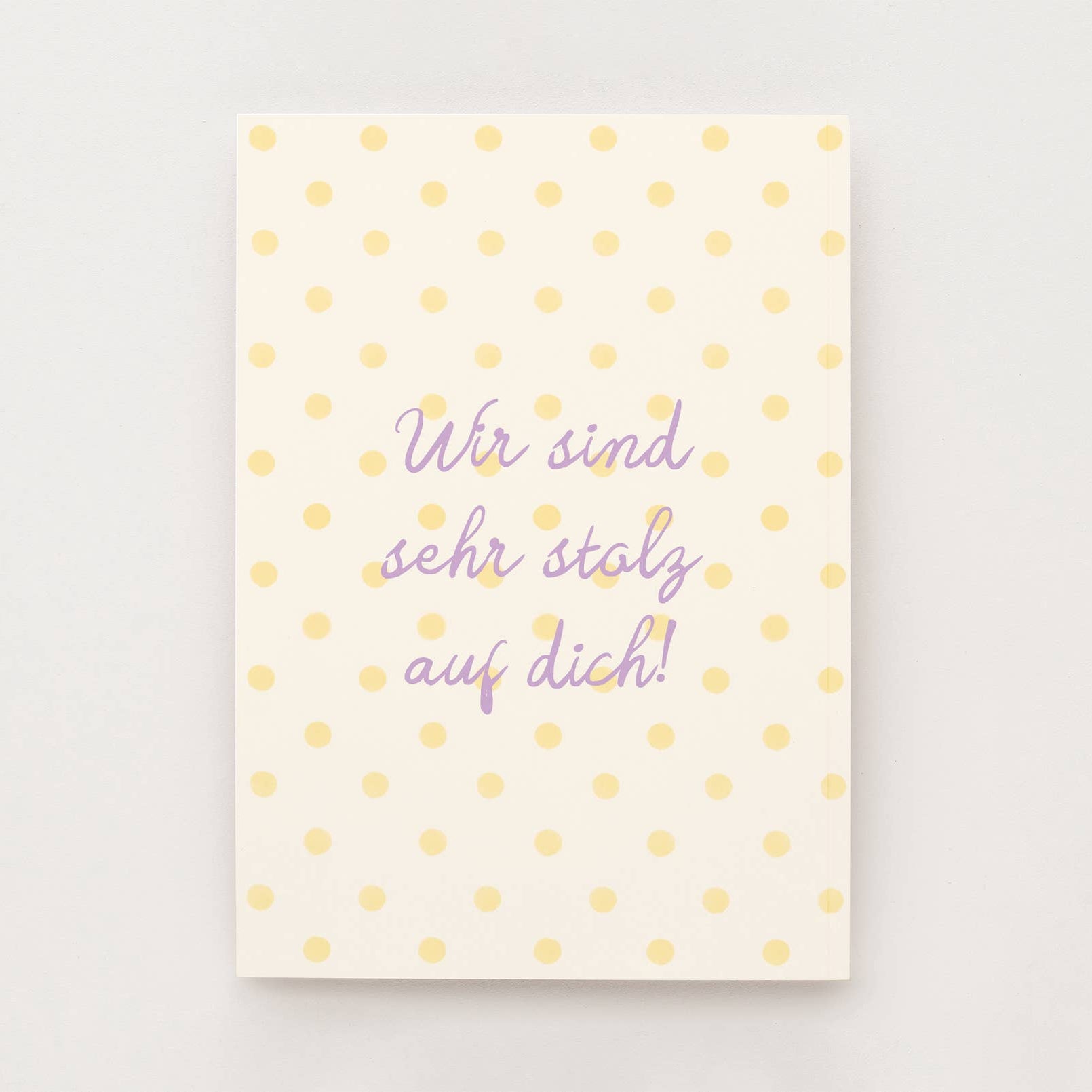 Cremefarbene Postkarte mit gelben Punkten und dem Schriftzug "Wir sind sehr stolz auf dich"